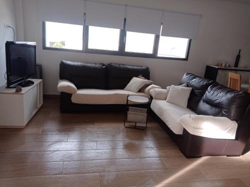 a living room with a leather couch and a television at Alojamiento de Jorge in Herencia