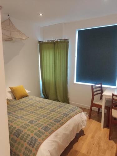 a bedroom with a bed and a table and a window at Garden Room in Cardigan