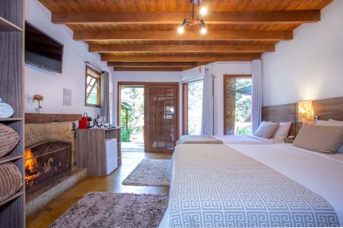 a bedroom with a large bed and a fireplace at Pousada Suiça Mineira Garden in Monte Verde
