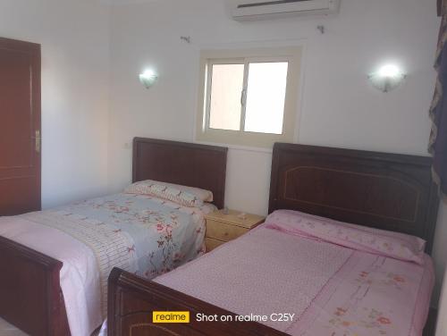 two beds in a small bedroom with a window at الفيروز in Hurghada