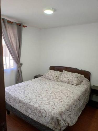 Schlafzimmer mit einem Bett mit weißer Bettwäsche und einem Fenster in der Unterkunft Arriendo diario Duplex La Serena in La Serena