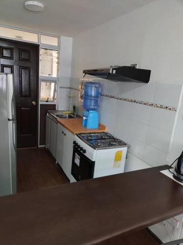 una pequeña cocina con fogones y jarra azul. en Arriendo diario Duplex La Serena en La Serena