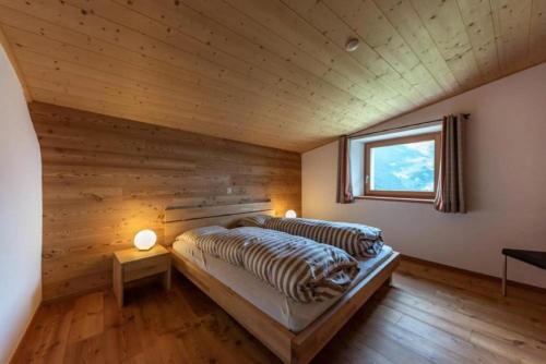 a bed in a room with a wooden wall at Monte Campell Dasura in Poschiavo
