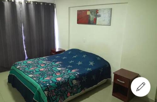 Schlafzimmer mit einem Bett mit blauer Decke und einem Tisch in der Unterkunft Departamentoswilson in Iquique