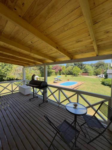 a large wooden deck with a grill and a pool at CABAÑAS Mony in Pucón