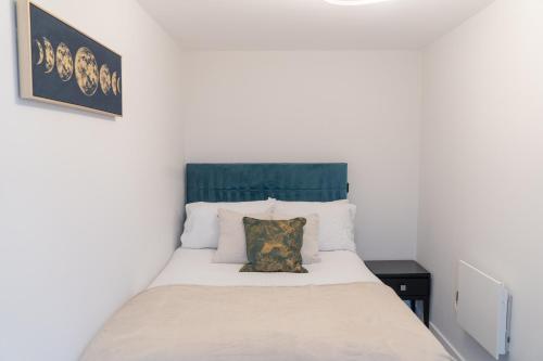 a bedroom with a white bed with a green headboard at Apex Lofts Suite - Modern 2 bed with rooftop terrace in Birmingham