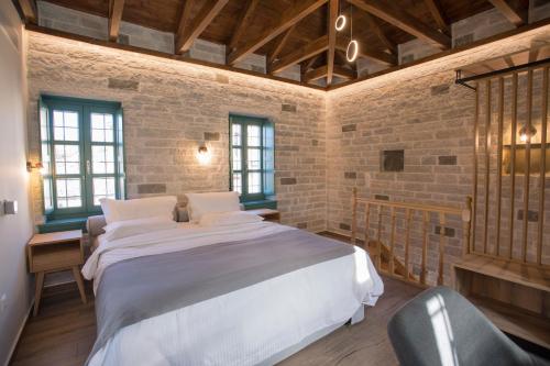 a bedroom with a large bed in a brick wall at MAKRIS Papigo Luxury suites in Papigko