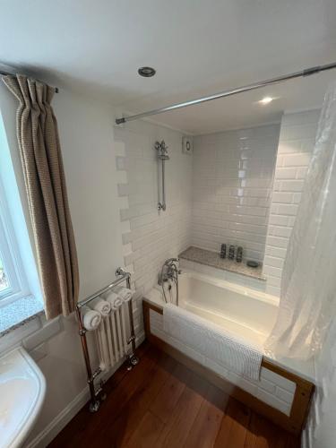 a white bathroom with a tub and a sink at Torside Holiday Cottage in Castleton