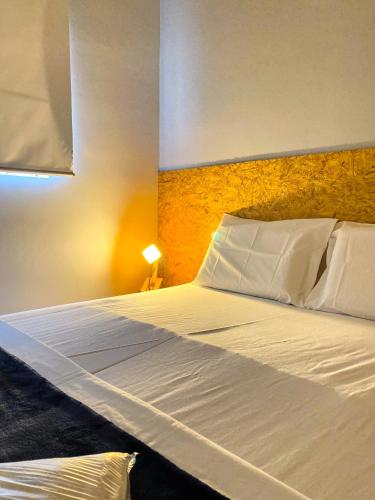 a bedroom with a large bed with white sheets and pillows at Lamparina Hostel in Sao Paulo