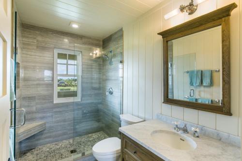 La salle de bains est pourvue d'un lavabo, de toilettes et d'un miroir. dans l'établissement Plantation-Style Home with Pool- Alekona Kauai, à Koloa