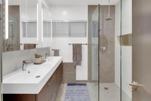 La salle de bains est pourvue d'un lavabo blanc et d'une douche. dans l'établissement New! Luxury 5BR, W/Arcade, Sauna, Views, Fire Pit!, à San Diego