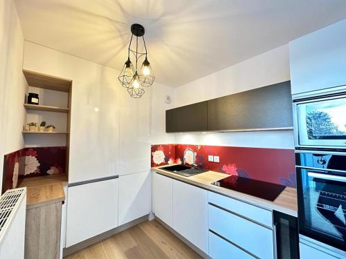 una cocina con armarios blancos y una lámpara de araña en La Frontalière en Ambilly