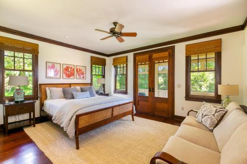 ein Schlafzimmer mit einem Bett, einem Sofa und Fenstern in der Unterkunft Charming Coastal Cottage in Kukuiula- Alekona Kauai in Koloa