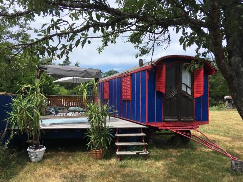 a blue and red train car parked next to a tree at Gîte et Roulotte dans les Vosges in Remiremont
