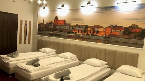 3 camas en una habitación con una pintura en la pared en Quick Trip Apartments Toruń, en Toruń