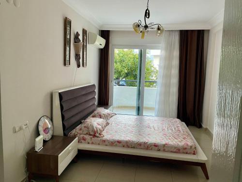 een slaapkamer met een groot bed en een raam bij Alva Sitesi Comfortable apartments by the sea in Alanya