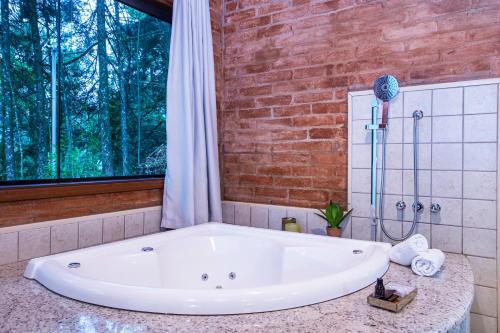 a large bath tub in a bathroom with a window at Pousada Suiça Mineira Garden in Monte Verde