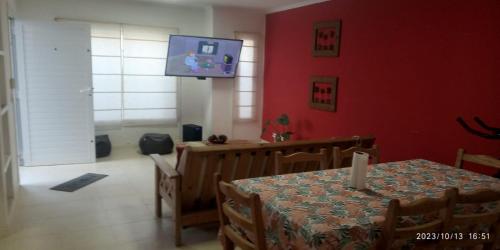 comedor con mesa y TV en una pared roja en ALQUILO CASA EN NECOCHEA en Necochea