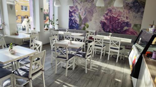 ein Restaurant mit weißen Tischen und Stühlen und einem Gemälde in der Unterkunft Apartmán Café u Kordulky in Ratíškovice