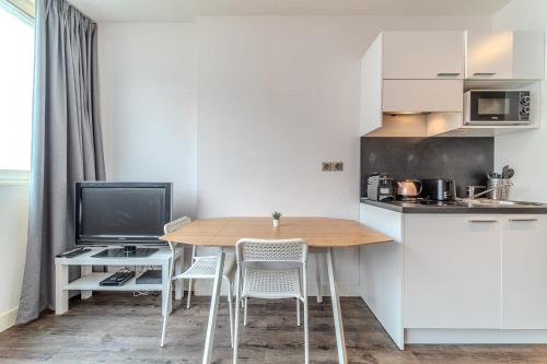 eine kleine Küche mit einem Holztisch und Stühlen in der Unterkunft Studio proche tête d'Or 2 personnes Villeurbanne in Villeurbanne