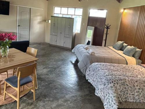 a hotel room with two beds and a table and chairs at Loft Del Fundo Del Abuelo in Cajamarca