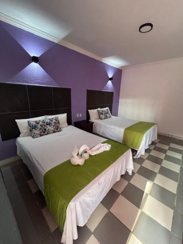 two beds in a room with purple and green at Hotel Capri Playa a una calle de la Playa Regatas in Veracruz