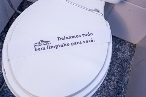 a sign on a toilet seat in a bathroom at Pousada Suiça Mineira Garden in Monte Verde