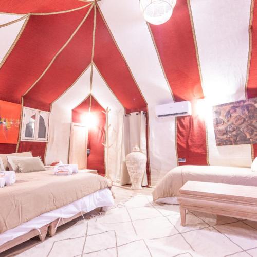 a bedroom with two beds and a red ceiling at Royal Luxury Cafe Du Sud in Merzouga