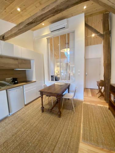 a dining room with a wooden table and a kitchen at Gîte et Roulotte dans les Vosges in Remiremont