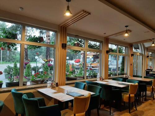 a restaurant with tables and chairs and windows at Hotel Pepa in Divčibare