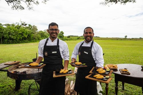 two men in aprons holding plates of food at El Tránsito Hotel Boutique in Concepción