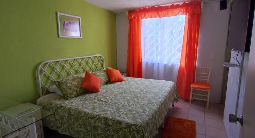 1 dormitorio con 1 cama con almohadas de color naranja y ventana en BONITA CASA EN BAHIA DE BANDERAS (BUCERIAS NAY), en Bucerías