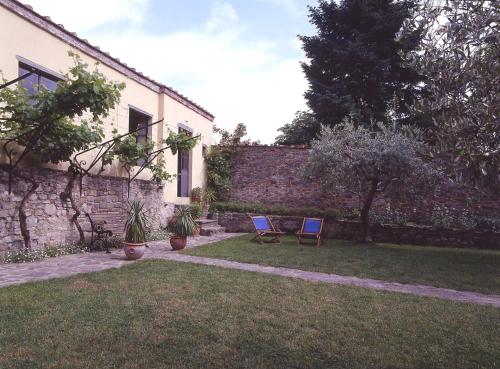 two chairs in a yard next to a brick wall at antica casa "le rondini" in Borgo a Buggiano