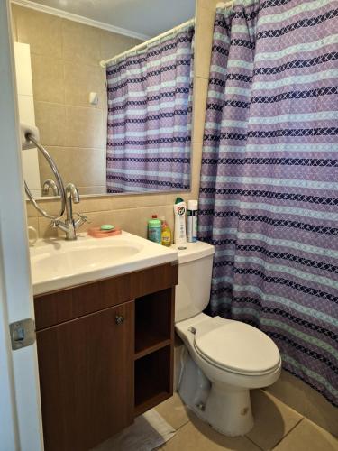 y baño con aseo, lavamanos y cortina de ducha. en Hospedaje casa Terracota en La Serena