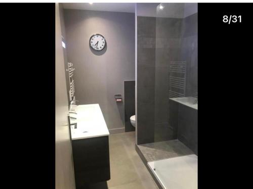 a bathroom with a clock on the wall and a toilet at Pavillon 1 à 4 personnes chez l’habitant parfait pour une famille in Bagneux