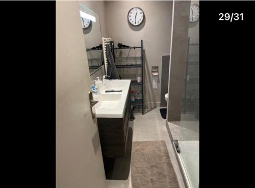 a bathroom with a sink and a clock on the wall at Pavillon 1 à 4 personnes chez l’habitant parfait pour une famille in Bagneux