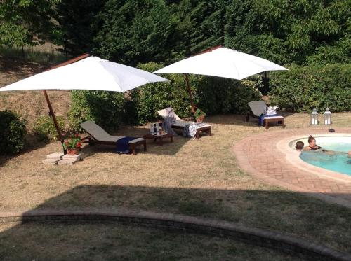 a pool with two umbrellas and people in a yard at B&B dell'Aviatore in San Liberato