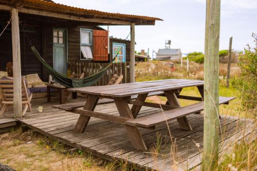eine Holzterrasse mit Hängematte und ein Haus in der Unterkunft Satori in Barra de Valizas