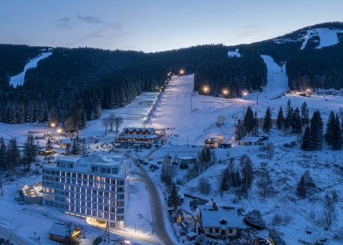 a view of a hotel in the snow at night at Apartment Snow & Spa Czarna Góra Resort in Sienna