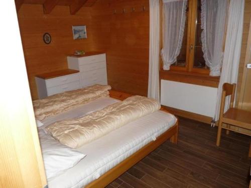 uma pequena cama num quarto com uma janela em Chalet Kiefer - b48527 em Grindelwald