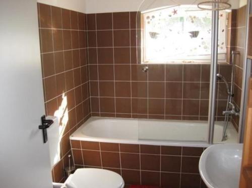 ein Badezimmer mit einer Badewanne, einem WC und einem Waschbecken in der Unterkunft Gemütliches Ferienhaus in Lindow Mark mit Garten und Grill - b48500 in Lindow