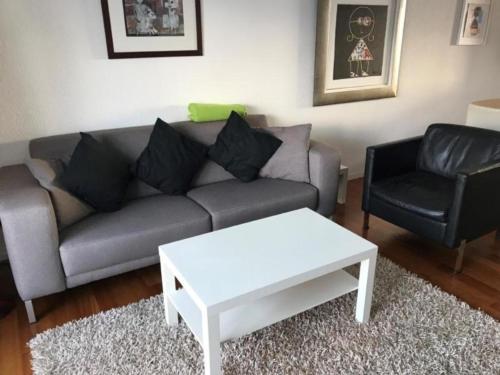ein Wohnzimmer mit einem Sofa, einem Tisch und einem Stuhl in der Unterkunft modern eingerichtete Ferienwohnung in Andermatt - b48523 in Andermatt