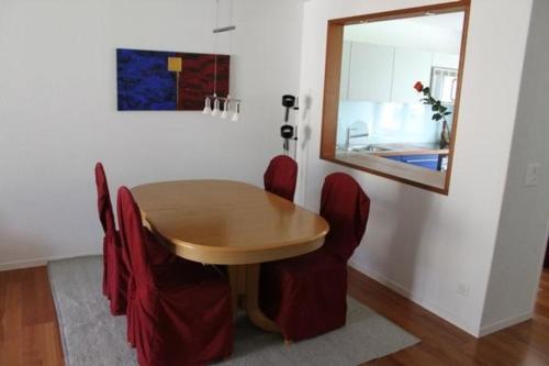 a dining room table with red chairs and a mirror at modern eingerichtete Ferienwohnung in Andermatt - b48523 in Andermatt