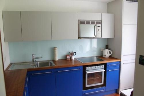 eine Küche mit blauen und weißen Schränken und einem Waschbecken in der Unterkunft modern eingerichtete Ferienwohnung in Andermatt - b48523 in Andermatt