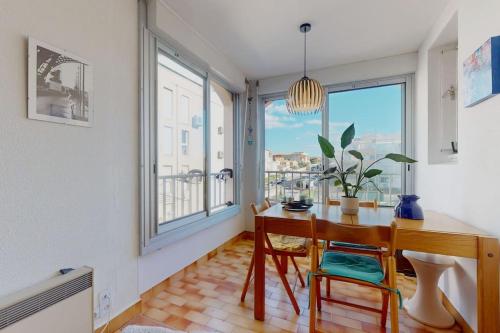 een eetkamer met een tafel en een aantal ramen bij Beau studio, plage, port. in Cap d'Agde