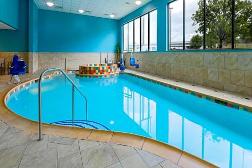 a large swimming pool with blue water in a building at Holiday Inn Express & Suites Downtown in Fort Worth