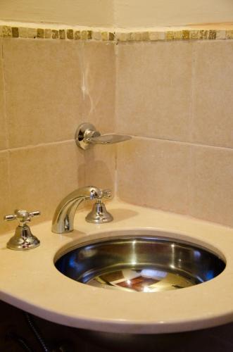 a silver sink in a bathroom with a tiled wall at Hosteria Felipa Pastor - Ex Munay Humahuaca in Humahuaca