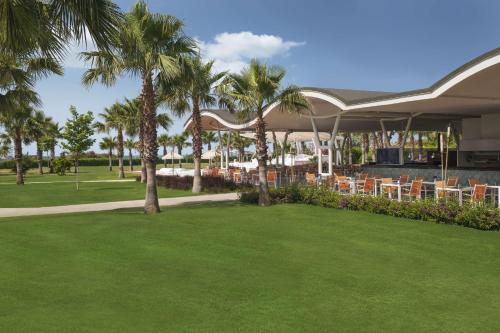 a restaurant with chairs and palm trees in a park at Hilton Dalaman Sarigerme Resort & Spa in Dalaman