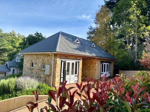 a small stone house with a black roof at The Coach House in Aldgate