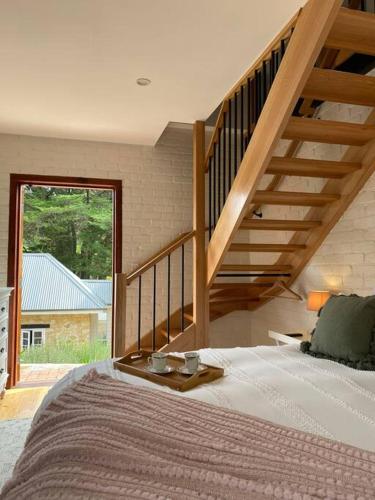 a bedroom with a bed and a wooden staircase at The Coach House in Aldgate